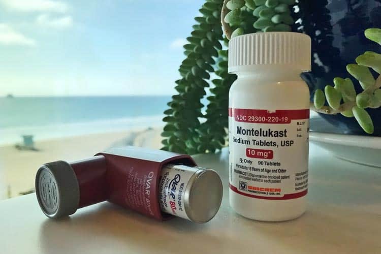 Singulair tablet bottle and Qvar inhaler prescription asthma medications with ocean and beach in background