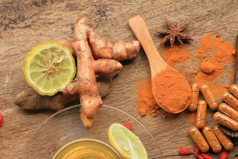 turmeric root next to powder and supplements