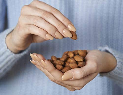 woman eating handful of almonds