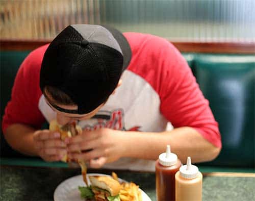 young man eating burger and fries