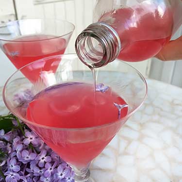 martini glass being filled with pink colored lemonade