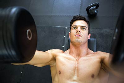 bodybuilder laying on bench lifting barbells