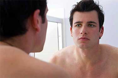 man looking in mirror at receding hairline