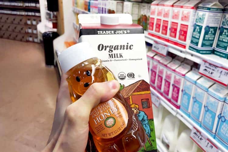 holding carton of organic milk and bottle of honey