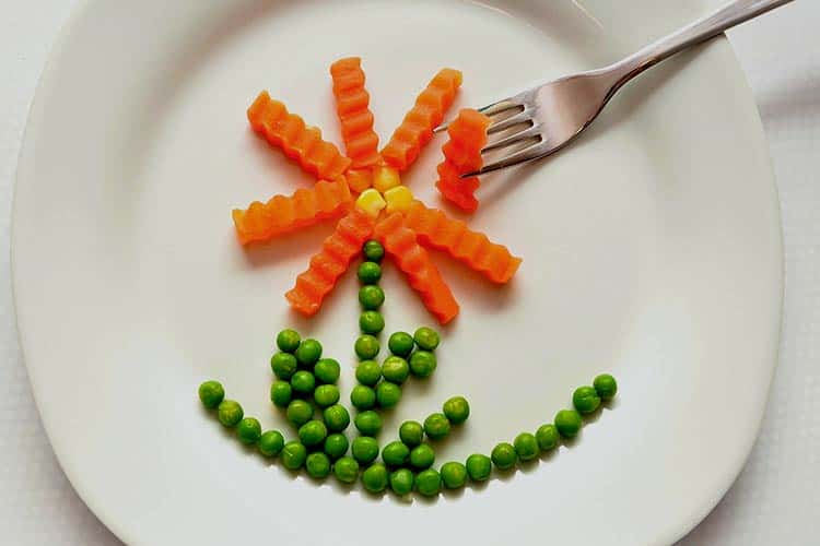 playing with peas and carrots on dinner plate