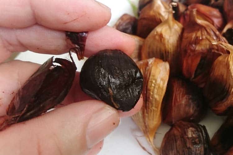 holding a raw black garlic clove