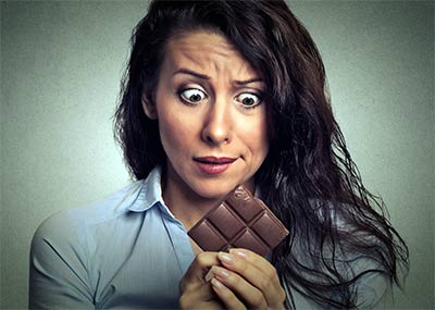 woman holding chocolate trying to resist