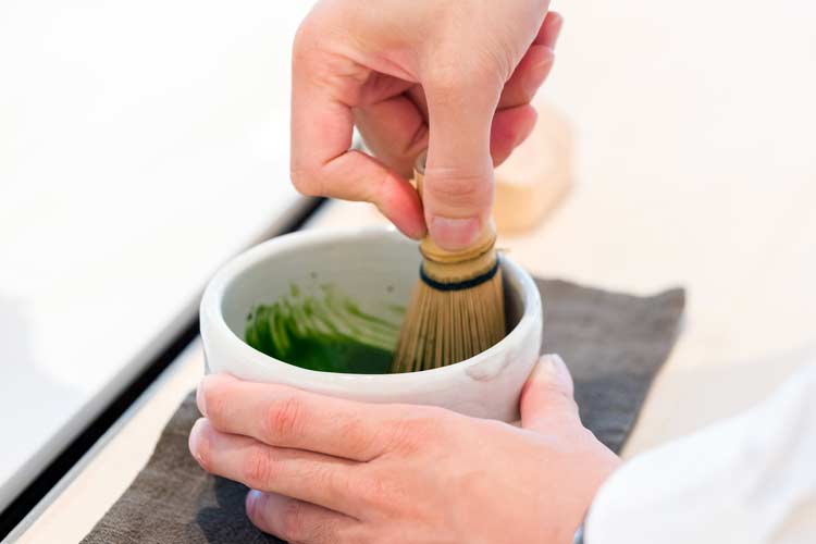 Japanese tea maker showing how to whisk matcha powder